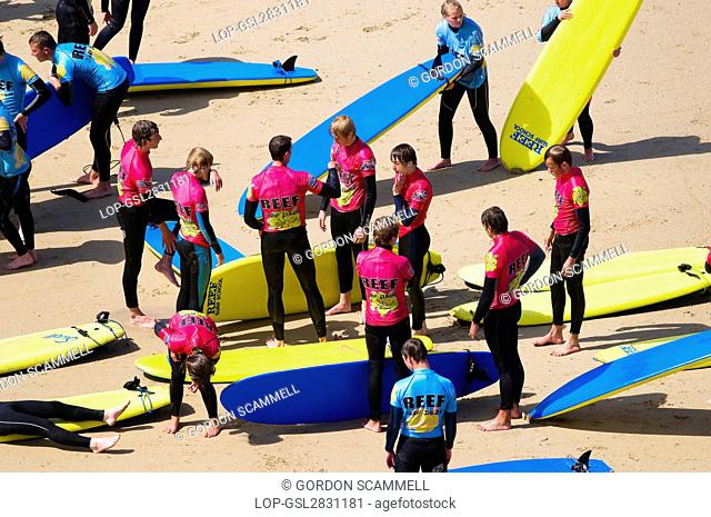 England, Cornwall, Newquay. Young people receiving instructions at a surf school on a beach in Newquay