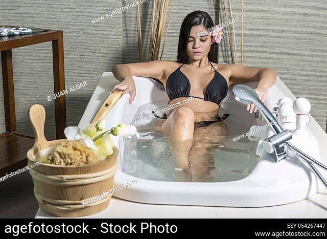 Beautiful sensual woman resting in healthy bath while enjoying time in massage center