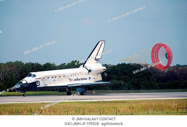 Space Shuttle Discovery's drag chute is deployed as the spacecraft rolls toward wheels stop on runway 15 of the Shuttle Landing Facility at NASA's Kennedy Space...