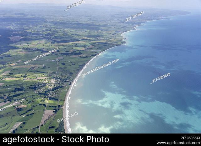 aerial, from a glider, of waves on beach at Ocean shore near village on coast , shot in bright spring light from at Hampden, Canterbury, South Island