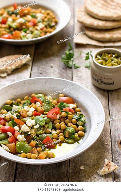 Chickpea salad made with broad beans, tomatoes, parsley and feta cheese next to green pepper relish