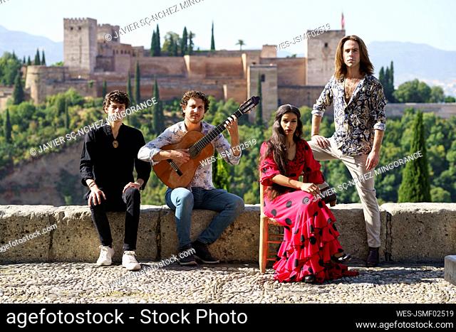 Flamenco musicians and dancers sitting on wall in front of Alhambra, Granada, Spain