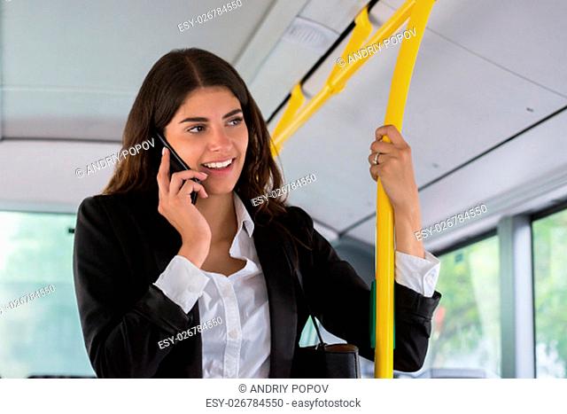 Happy Young Businesswoman Talking On Smartphone While Traveling By Public Transport