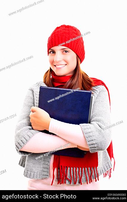 Portrait of a beautiful smiling female student in winter clothes holding a book, isolated on white background. I?m ready for winter exam season