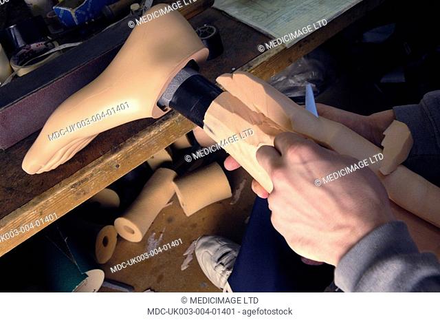 A technician carves an prosthetic leg into shape
