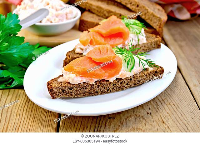 Sandwich with salmon and cream in a dish with cucumber