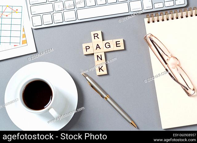 Rank page concept with letters on cubes. Still life of office workplace with crossword. Flat lay grey surface with pc keyboard and cup of coffee