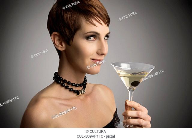 Studio portrait of woman looking sideways holding cocktail