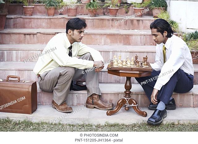 Side profile of two businessmen playing chess