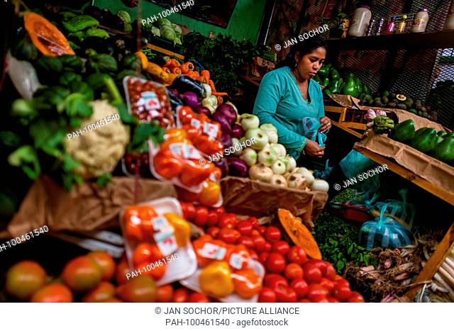 A Colombian vendor packs fresh vegetables into a plastic bag at the market of Paloquemao in Bogota, Colombia, 25 November 2017. | usage worldwide