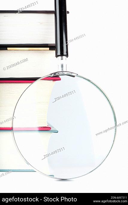 Closeup view of thick books and magnifying glass isolated over white background