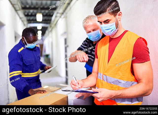 Drei Arbeiter mit Mundschutz wegen Covid-19 am Wareneingang mit Checkliste