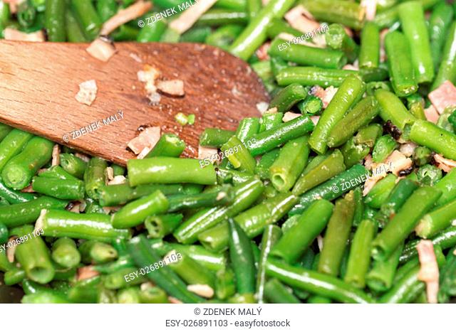 home roasting fresh green beans with bacon and spices on pan as dish to meat