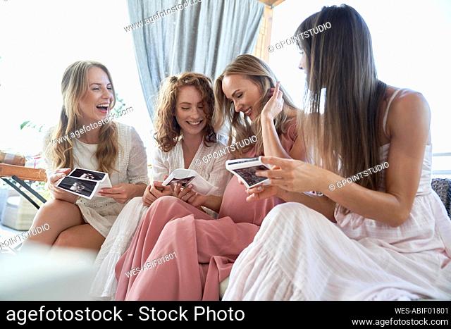 Smiling pregnant woman with friends sharing her ultrasound scan result at baby shower