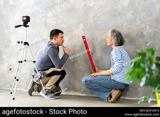 Man and woman discussing by gray wall at new home