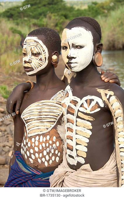 Two Surma girls with facial and body painting and ear plates, Kibish, Omo River Valley, Ethiopia, Africa