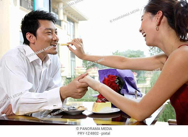 Mid adult man holding young women's hand on restaurant table