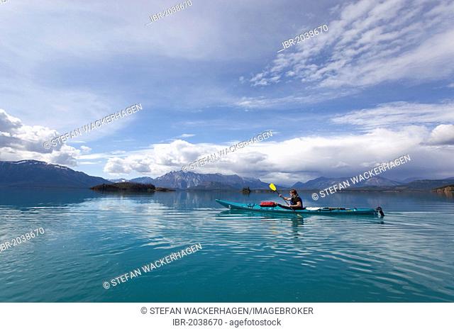 Young woman in a sea kayak, paddling, sea kayaking, mountains behind, Tagish Highland, Atlin Lake, British Columbia, Canada, America