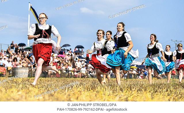 Several participants of the traditional shepherd race run with water buckets on top of their heads over a field in Markgroeningen, Germany, 26 August 2017