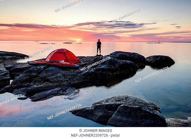 Man standing by tent at dusk