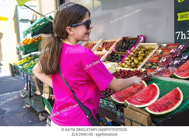 Young teen, preteen smiling and looking at the outdoor window front store of a local french grocery store