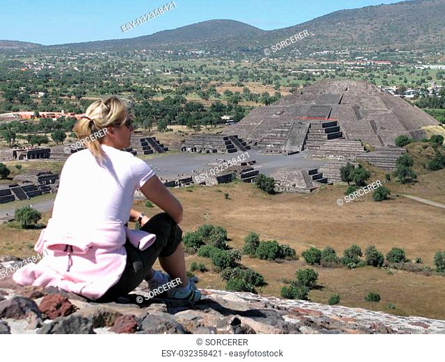 Young woman sitting with a view onto the Pyramid of the Moon in Teotihuacan, Mexico