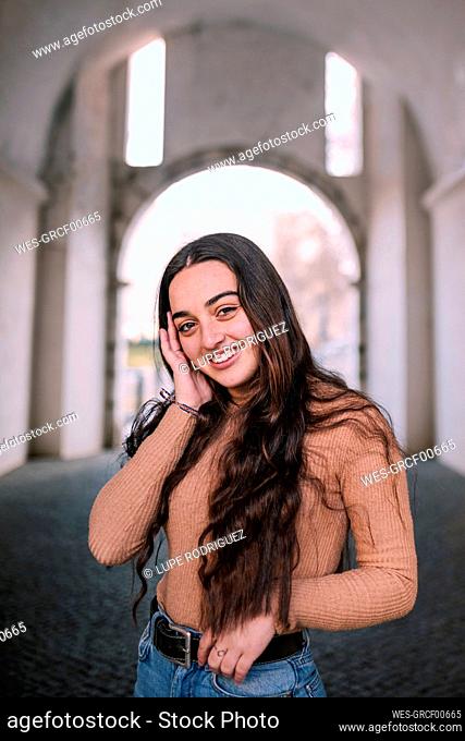 Smiling teenage girl with long hair standing on footpath in tunnel