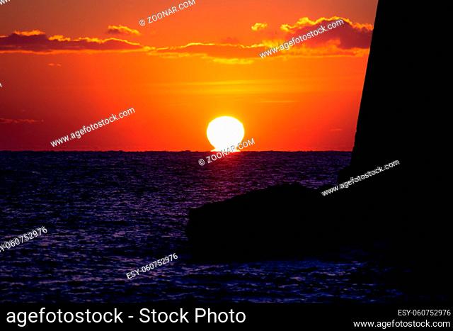 Sun melting into the ocean in deep red orange sky along the fortress wall at Dubrovnik, Croatia