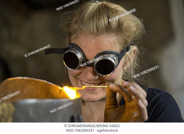 young female blacksmith with goggles, soldering metal