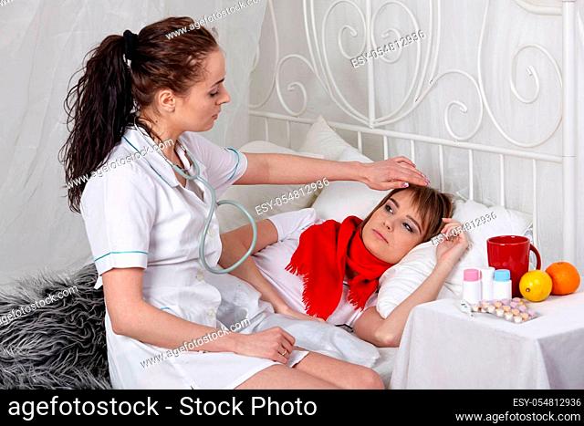 The doctor examines the ill girl lying in a bed. Selective focus