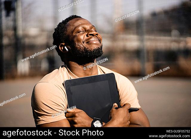 Smiling handsome man with digital tablet during sunny day