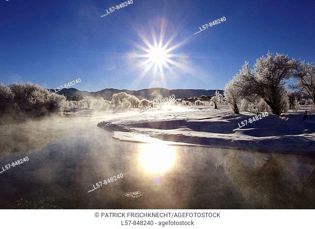 Winter landscape with hoarfrost, steeming river, brilliant sunshine and blue sky, Utah, USA