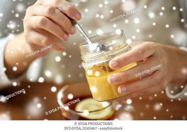 close up of woman adding honey to tea with lemon