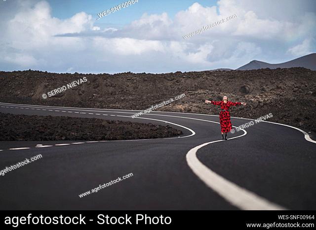 Carefree woman with arms outstretched standing on road at Los Hervideros, Lanzarote, Spain