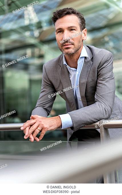 Businessman in the city leaning on railing