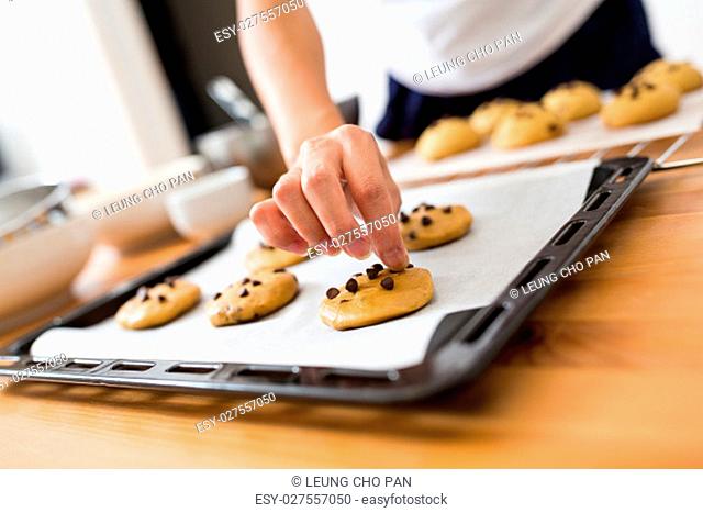 Woman adding chocolate bean on cookies