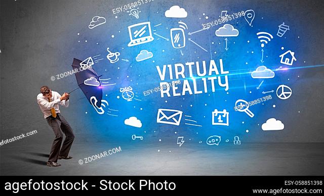Businessman defending with umbrella from VIRTUAL REALITY inscription, modern technology concept