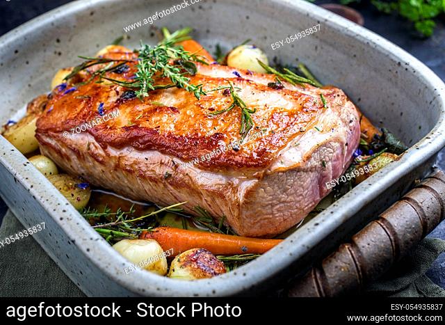 Traditional roasted dry aged veal tenderloin with carrots and onions offered as closeup in a saucepan