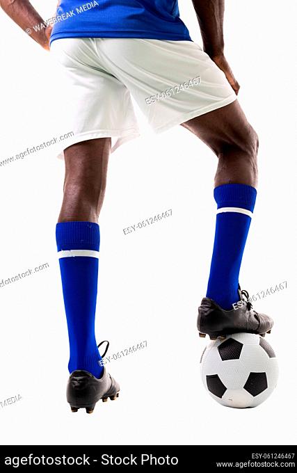 Low section of young african american male soccer player stepping on ball over white background
