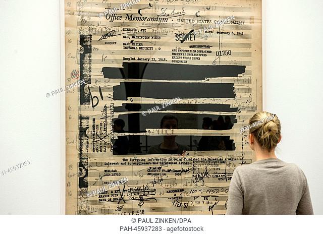 A woman stands at an over-sized sheet of music by composer Hanns Eisler that has been covered over with an FBI file at Hamburger Bahnhof in Berlin,  Germany