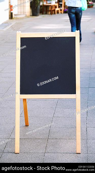 empty blank customer stopper blackboard advertising sign or menu board standing on sidewalk in city