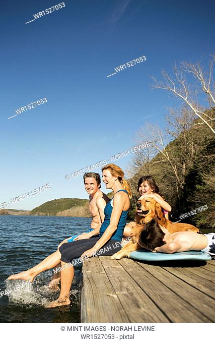 A family and their retriever dog on a jetty by a lake