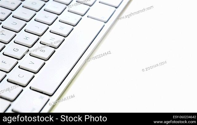 Modern computer keyboard with white keys. Side view with copy space on white background