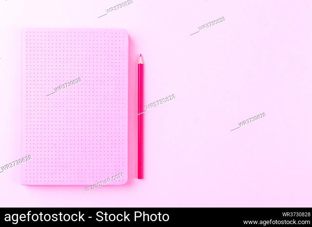 Diary or notepad with red pencil on pink background, flat lay copy space