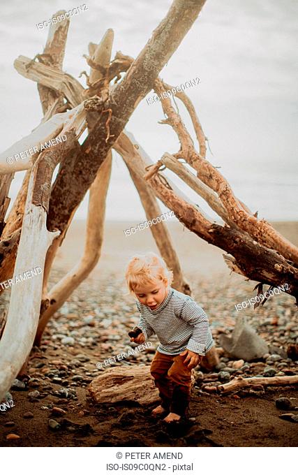 Toddler playing beside wickiup on beach