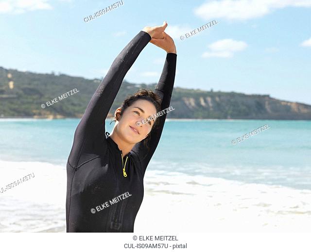 Surfer stretching on beach, Roadknight, Victoria, Australia