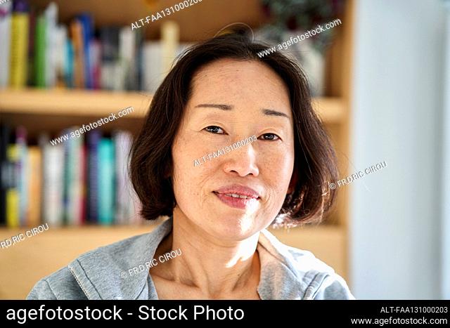 Senior Asian woman looking at the camera while sitting indoors