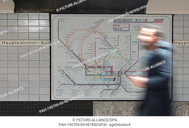 09 July 2019, Hamburg: A man walks along a map in the main station with the route network plan of the rapid-transit railway and regional traffic