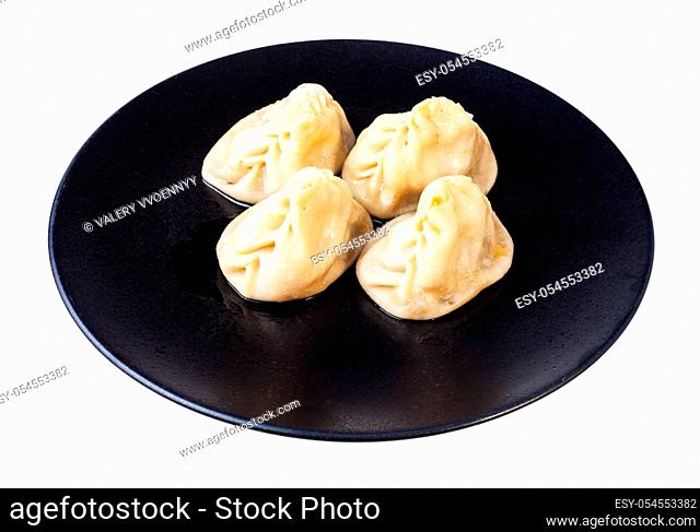 portion of cooked Manti (type of dumpling in turkic cuisine) on black plate isolated on white background