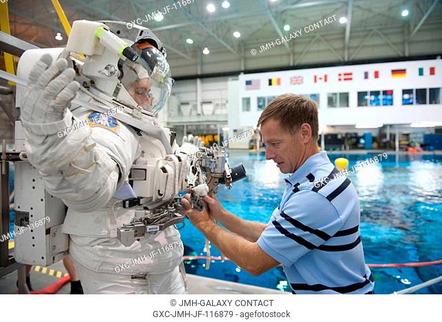 NASA astronaut Chris Ferguson, STS-135 commander, helps NASA astronaut Sandy Magnus, mission specialist, don a training version of her Extravehicular Mobility...
